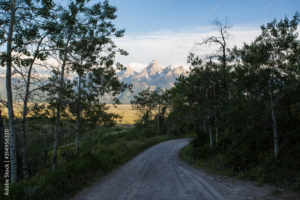 A road through the mountains looking at the mountains in Grand Teton National Park. A road through the mountains looking at the mountains in Grand Teton National Park.