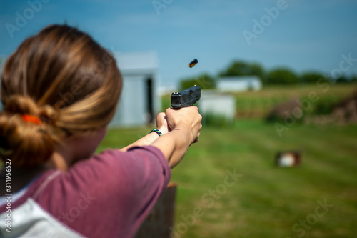 young woman pointing pistol downrange with ejected casing photo