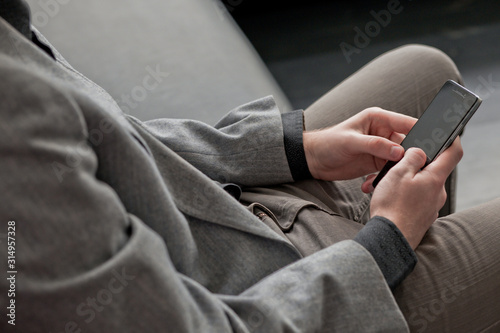 young man's hands hold black smartphone with dark screen with protective glass. Online shopping on Internet using smartphone.