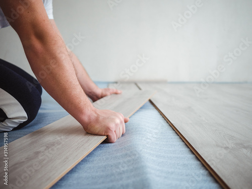 The repair process in the apartment. Man laying laminate flooring