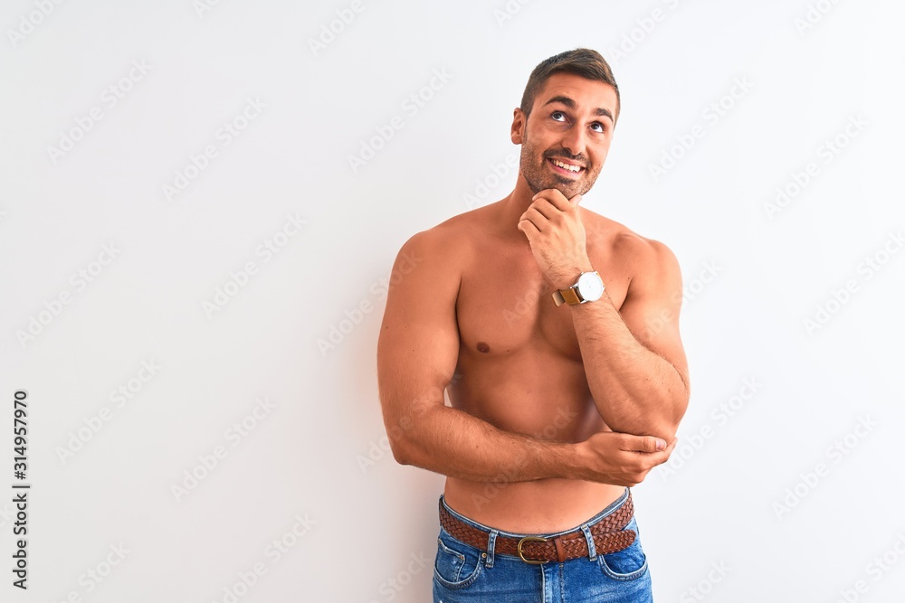 Young handsome shirtless man showing muscular body over isolated background with hand on chin thinking about question, pensive expression. Smiling with thoughtful face. Doubt concept.