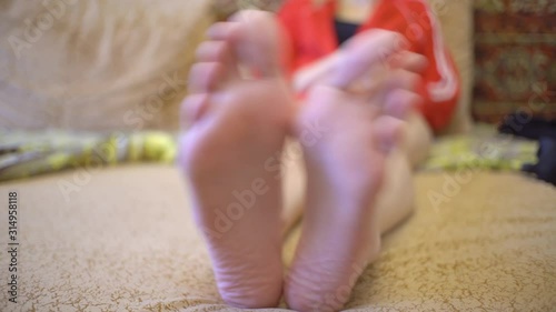 A woman shakes her bare feet lying on the bed. He plays in a good mood. photo