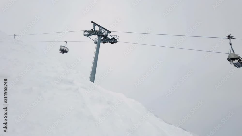 Moving ski chair lift station on mountain top in cloudy winter day Moving ski chair lift station on mountain top in cloudy winter day