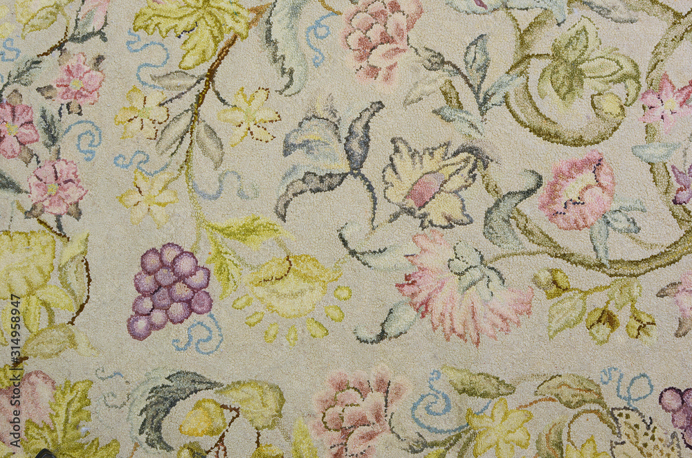 Detail of a vintage wool hooked rug with a botanical motiff with flowers, fruit and leafy vines