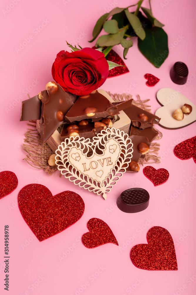 Valentine's day background with red hearts, chocolate candies and red rose on a pink background. Romantic atmosphere. Love symbols. Valentine's day background with red hearts, chocolate candies and red rose on a pink background. Romantic atmosphere. Love symbols.