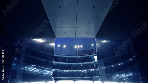Fototapeta Naklejka Na Ścianę i Meble -  Night architecture - building with glass facade. Modern building in  business district. Concept of economics, financial. Photo of commercial office building exterior. Abstract image of office building