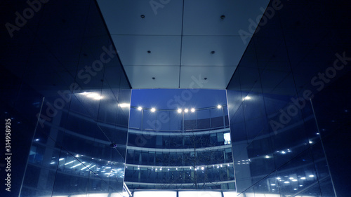 Night architecture - building with glass facade. Modern building in business district. Concept of economics, financial. Photo of commercial office building exterior. Abstract image of office building