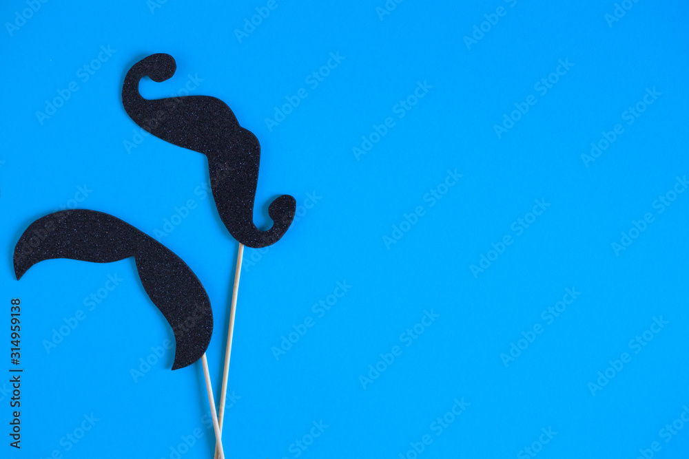 Fototapeta premium Paper mustache on a stick on a blue background. Holiday concept