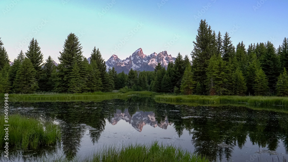 wide shot of grand teton and a pond at schwabacher landing at sunrise