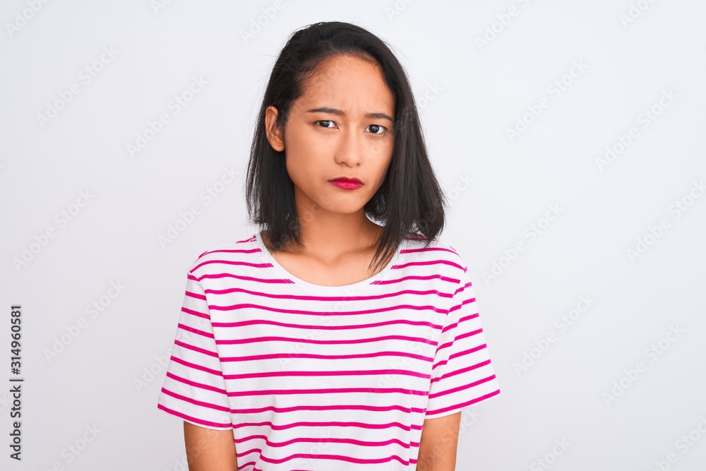 Young chinese woman wearing striped t-shirt standing over isolated white background skeptic and nervous, frowning upset because of problem. Negative person. Young chinese woman wearing striped t-shirt standing over isolated white background skeptic and nervous, frowning upset because of problem. Negative person.