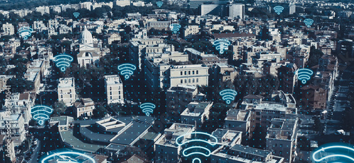Digital city of future concept. Aerial view of European cityscape with wireless communication networks WI-FI neon symbols, IoT Internet of Things, Big Data web connections in all buildings and houses.