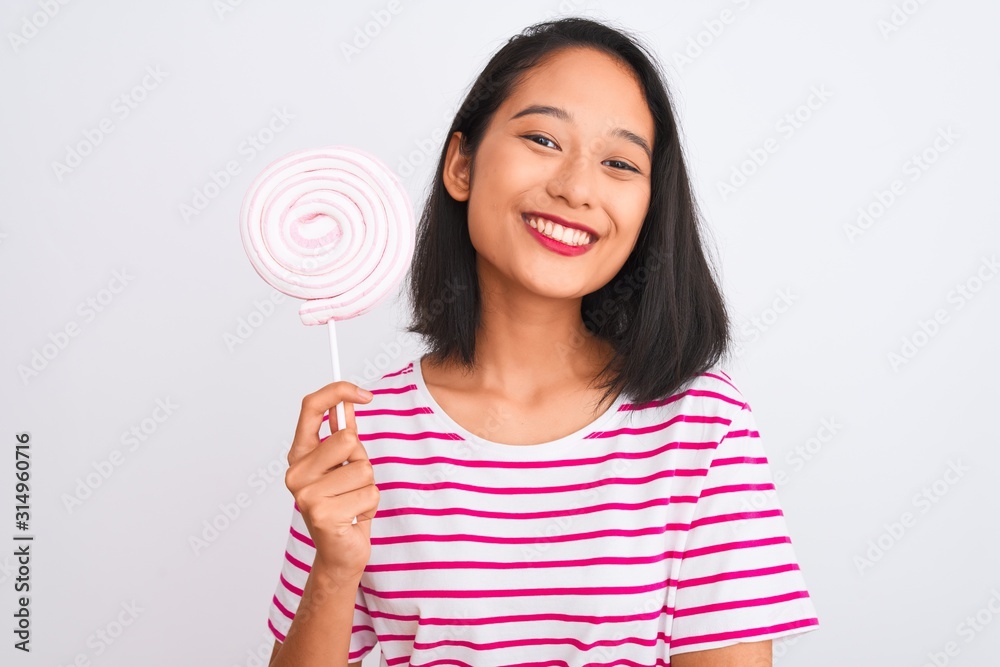 Young beautiful chinese woman eating lollipop standing over isolated white background with a happy face standing and smiling with a confident smile showing teeth Young beautiful chinese woman eating lollipop standing over isolated white background with a happy face standing and smiling with a confident smile showing teeth