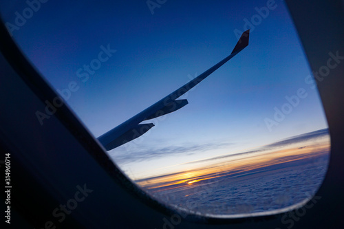 beautiful saturated sunset above the clouds on the porthole of the plane, the road to a new life, pacifying wallpaper, littered horizon 