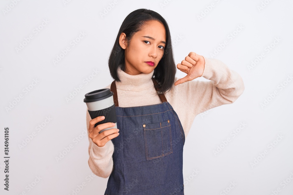 Beautiful barista chinese woman wearing apron holding coffee over isolated white background with angry face, negative sign showing dislike with thumbs down, rejection concept