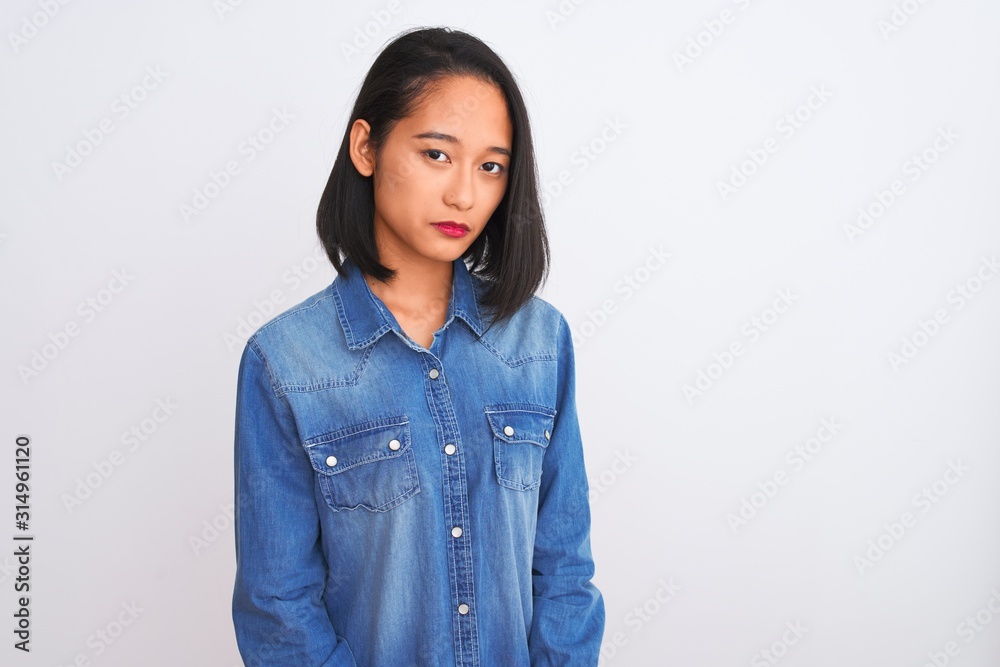 Young beautiful chinese woman wearing denim shirt standing over isolated white background depressed and worry for distress, crying angry and afraid. Sad expression. Young beautiful chinese woman wearing denim shirt standing over isolated white background depressed and worry for distress, crying angry and afraid. Sad expression.