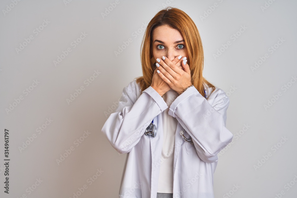 Redhead caucasian doctor woman wearing stethoscope over isolated background shocked covering mouth with hands for mistake. Secret concept. Redhead caucasian doctor woman wearing stethoscope over isolated background shocked covering mouth with hands for mistake. Secret concept.