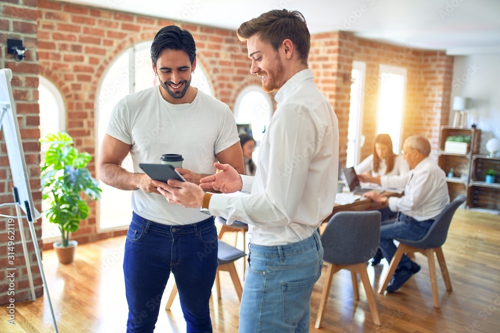 Business workers smiling happy. Standing with smile on face working together using tablet at the office Business workers smiling happy. Standing with smile on face working together using tablet at the office