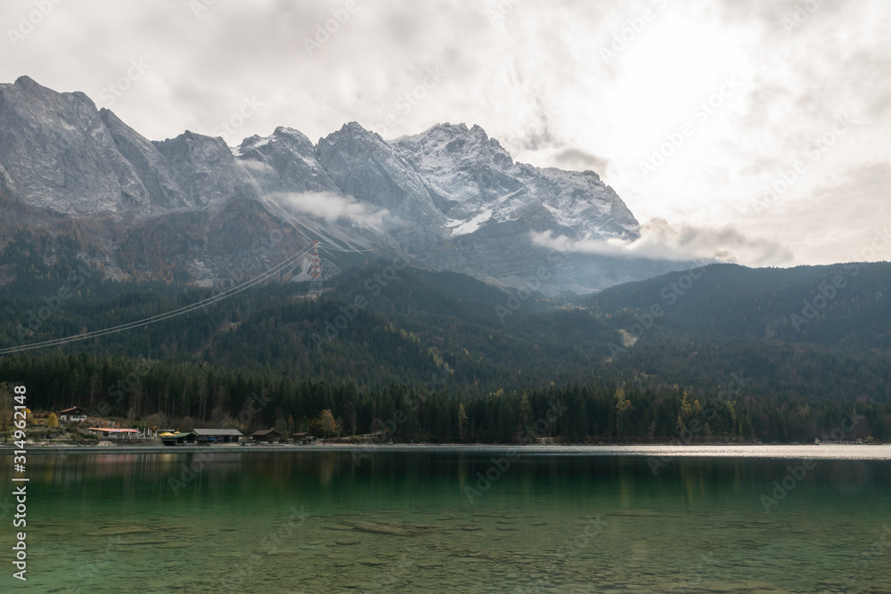The sun behind the clouds, at Eibsee in front of Zugspitze