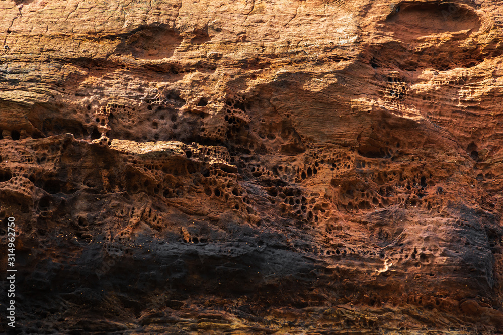 Rocks from black and orange sandstone with traces of destruction, erosion. Abstract stone texture Rocks from black and orange sandstone with traces of destruction, erosion. Abstract stone texture