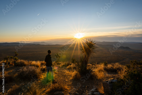 Man taking in the sunrise on a solo outdoors hike in Joshua tree with lens flare from sun | Joshua Tree Hiking