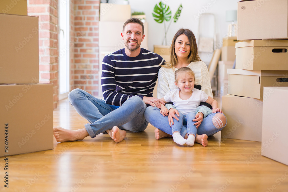 Beautiful family sitting on the floor playing with his kid at new home around cardboard boxes Beautiful family sitting on the floor playing with his kid at new home around cardboard boxes