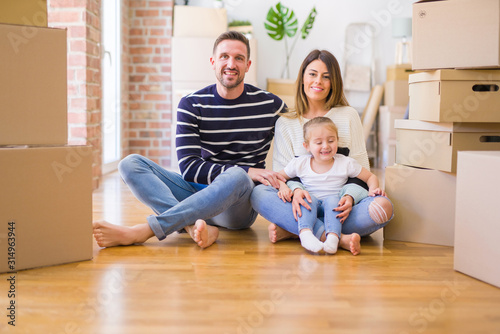 Beautiful family sitting on the floor playing with his kid at new home around cardboard boxes © Krakenimages.com