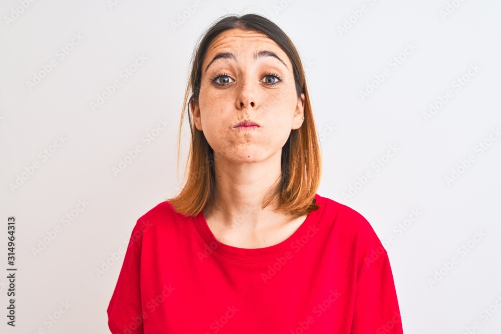 Beautiful redhead woman wearing casual red t-shirt over isolated background puffing cheeks with funny face. Mouth inflated with air, crazy expression. Beautiful redhead woman wearing casual red t-shirt over isolated background puffing cheeks with funny face. Mouth inflated with air, crazy expression.
