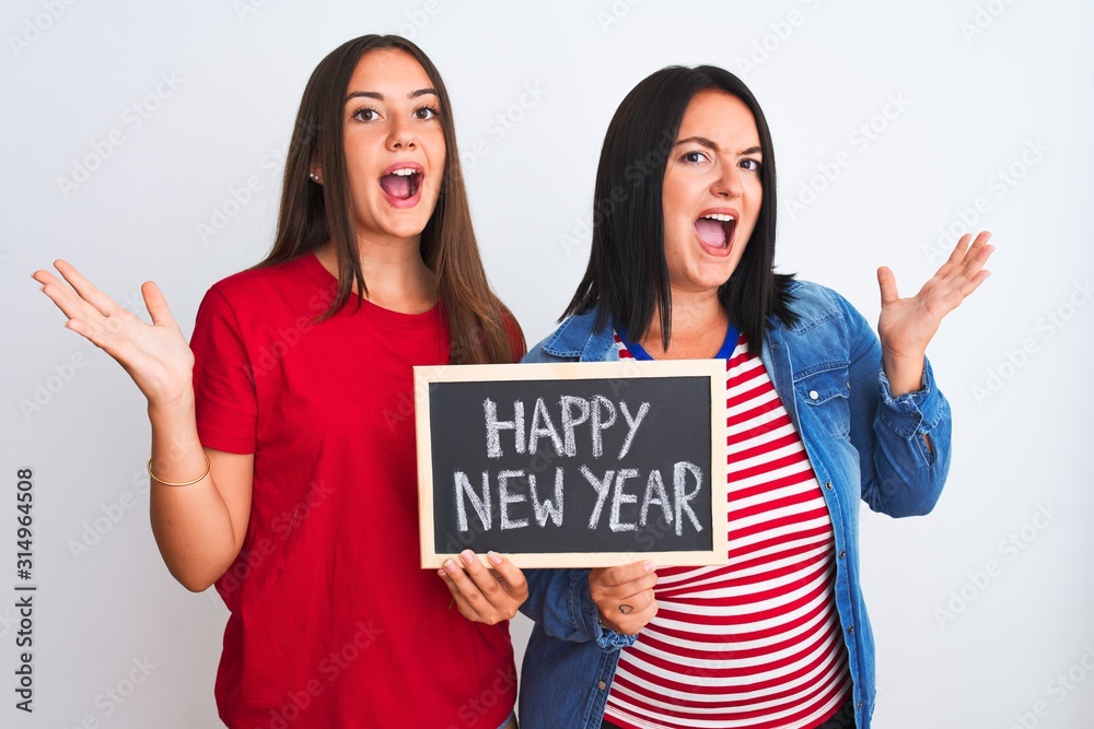 Beautiful women holding blackboard happy new year message over isolated white background very happy and excited, winner expression celebrating victory screaming with big smile and raised hands Beautiful women holding blackboard happy new year message over isolated white background very happy and excited, winner expression celebrating victory screaming with big smile and raised hands