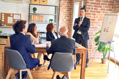 Group of business workers smiling happy and confident in a meeting. Working together looking at presentation using board and charts at the office.