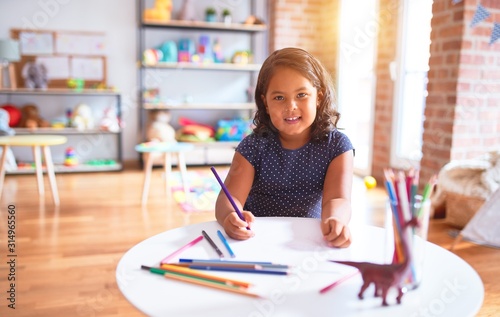 Beautiful toddler girl drawing cute draw using colored pencils at kindergarten