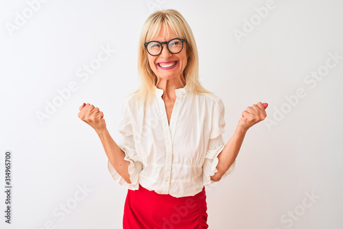 Middle age businesswoman wearing shirt and glasses standing over isolated white background very happy and excited doing winner gesture with arms raised, smiling and screaming for success. Celebration