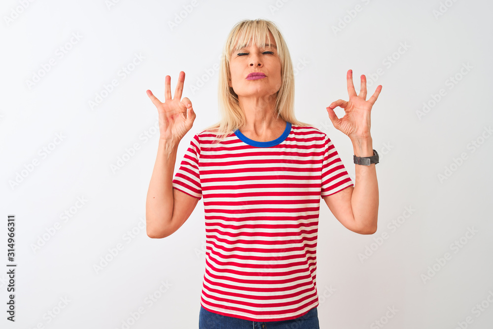 Middle age woman wearing casual striped t-shirt standing over isolated white background relax and smiling with eyes closed doing meditation gesture with fingers. Yoga concept. Middle age woman wearing casual striped t-shirt standing over isolated white background relax and smiling with eyes closed doing meditation gesture with fingers. Yoga concept.
