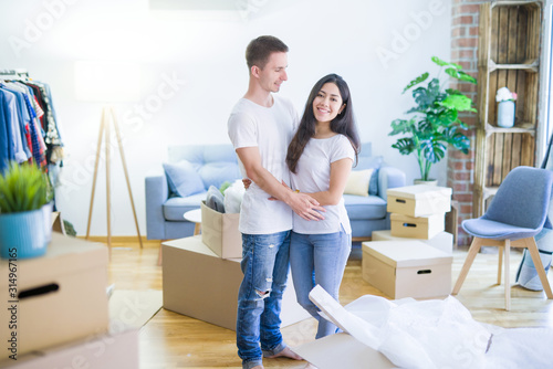 Young beautiful couple hugging at new home around cardboard boxes © Krakenimages.com