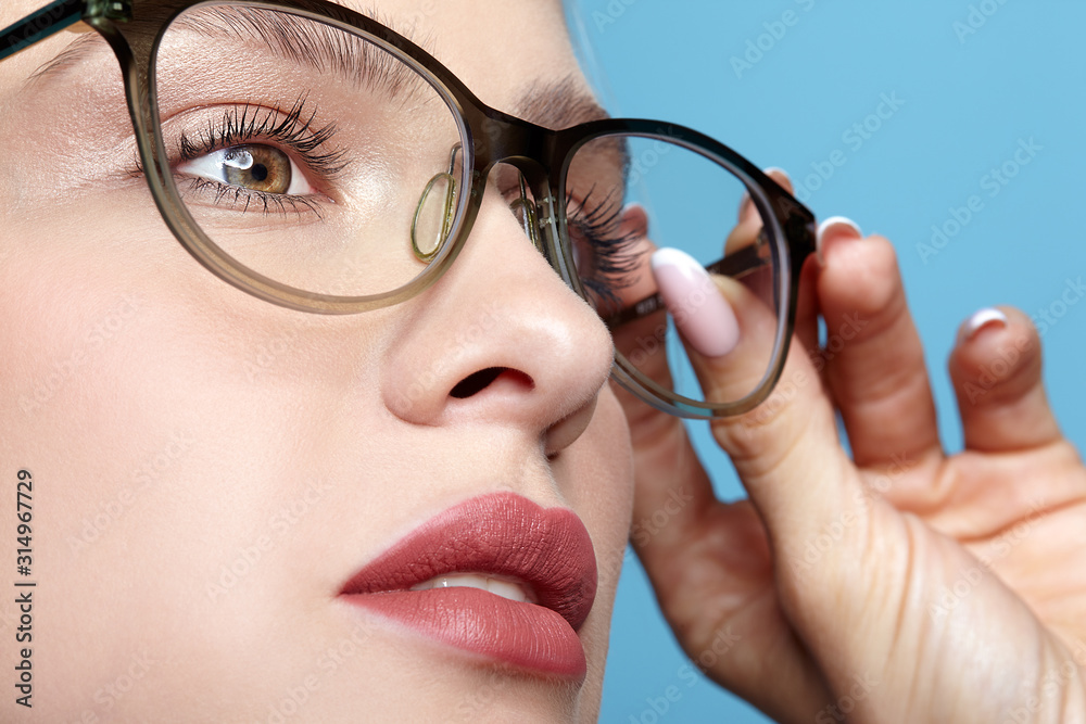 Close-up portrait of attractive young woman in glasses on blue background Close-up portrait of attractive young woman in glasses on blue background