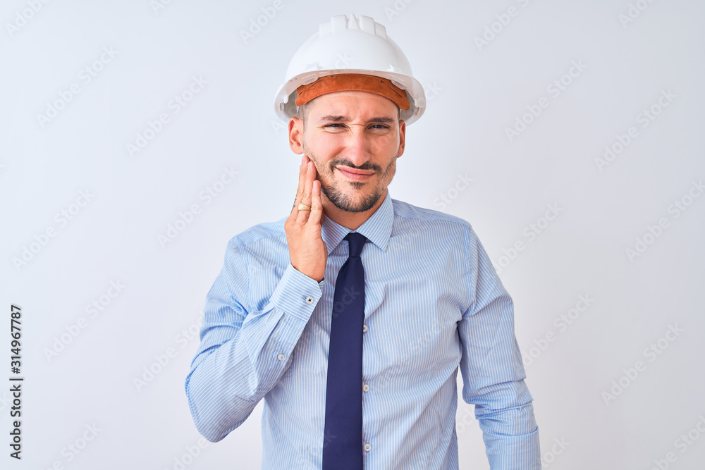 Young business man wearing contractor safety helmet over isolated background touching mouth with hand with painful expression because of toothache or dental illness on teeth. Dentist concept. Young business man wearing contractor safety helmet over isolated background touching mouth with hand with painful expression because of toothache or dental illness on teeth. Dentist concept.