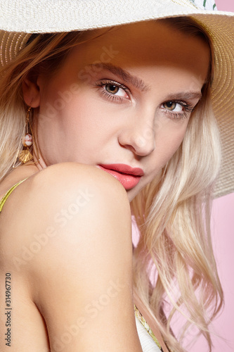 Portrait of a attractive young woman in summer hat on pink background
