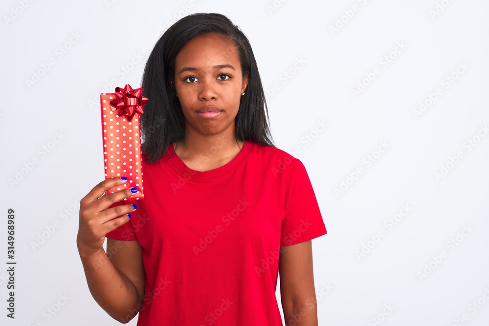 Young african american woman holding birthday present over isolated background with a confident expression on smart face thinking serious Young african american woman holding birthday present over isolated background with a confident expression on smart face thinking serious