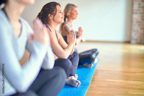Young beautiful group of sportswomen practicing yoga at gym