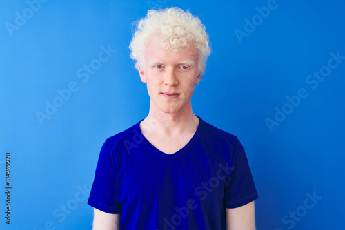 Photos Young albino blond man wearing casual t-shirt standing over isolated blue background with serious expression on face