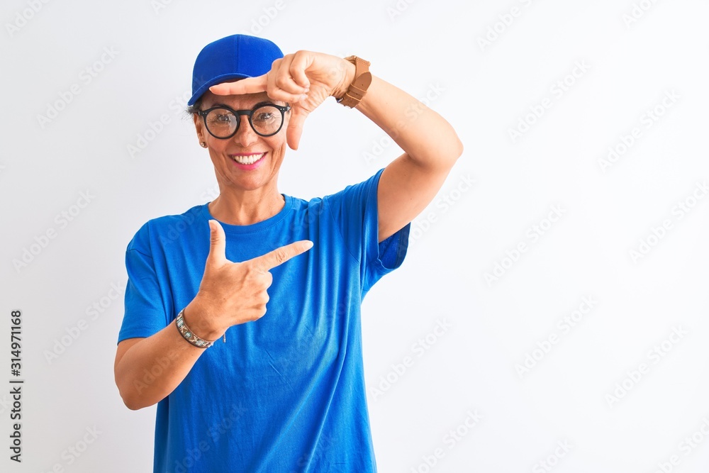 Senior deliverywoman wearing cap and glasses standing over isolated white background smiling making frame with hands and fingers with happy face. Creativity and photography concept.