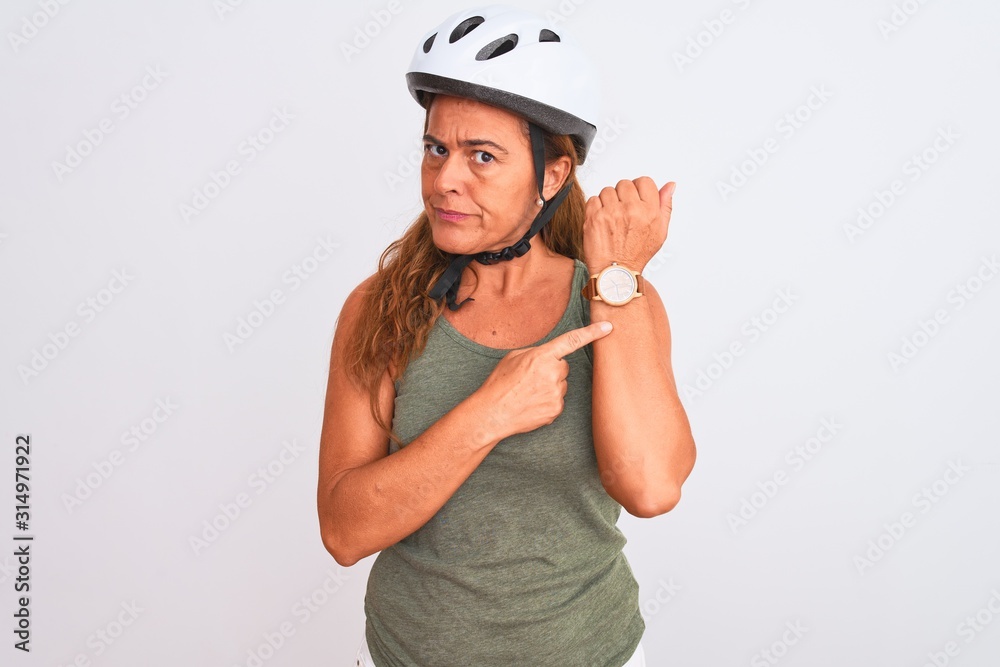 Middle age mature cyclist woman wearing safety helmet over isolated background In hurry pointing to watch time, impatience, looking at the camera with relaxed expression Middle age mature cyclist woman wearing safety helmet over isolated background In hurry pointing to watch time, impatience, looking at the camera with relaxed expression
