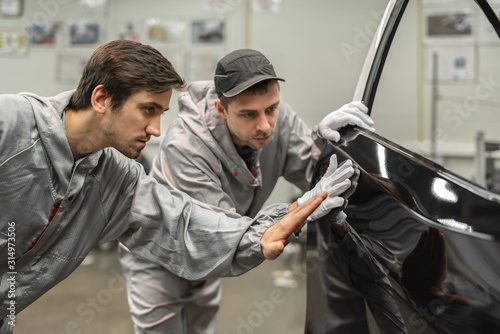 An employee of the quality Department of the car body paint shop provides training on quality control.