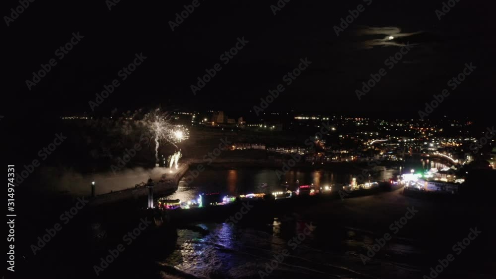 Fireworks over Whitby, a popular tourist destination on the Yorkshire Heritage Coast, UK. Moving aerial footage with large red fireworks at the end. Fireworks over Whitby, a popular tourist destination on the Yorkshire Heritage Coast, UK. Moving aerial footage with large red fireworks at the end.