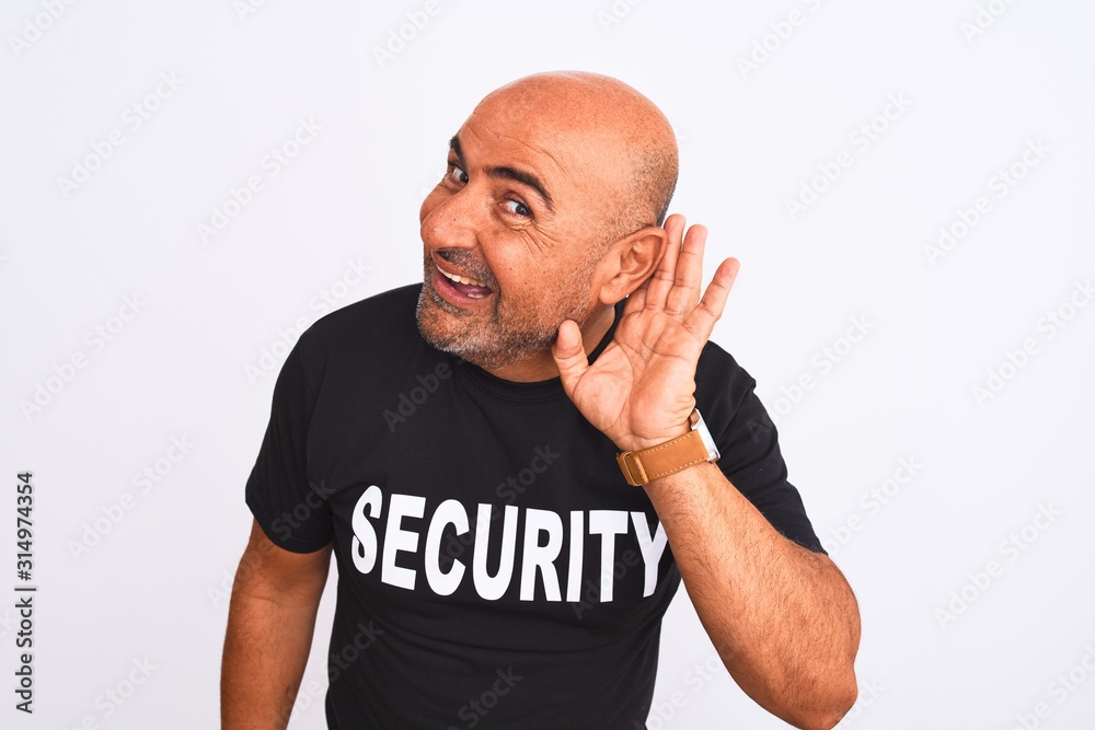 Middle age safeguard man wearing security uniform standing over isolated white background smiling with hand over ear listening an hearing to rumor or gossip. Deafness concept. Middle age safeguard man wearing security uniform standing over isolated white background smiling with hand over ear listening an hearing to rumor or gossip. Deafness concept.