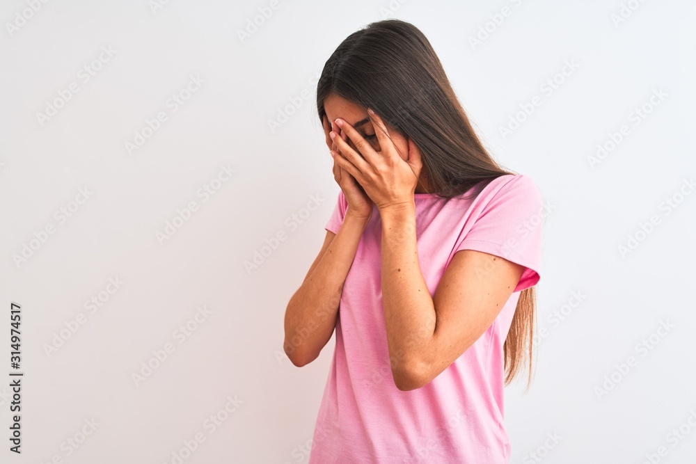 Young beautiful woman wearing pink casual t-shirt standing over isolated white background with sad expression covering face with hands while crying. Depression concept. Young beautiful woman wearing pink casual t-shirt standing over isolated white background with sad expression covering face with hands while crying. Depression concept.