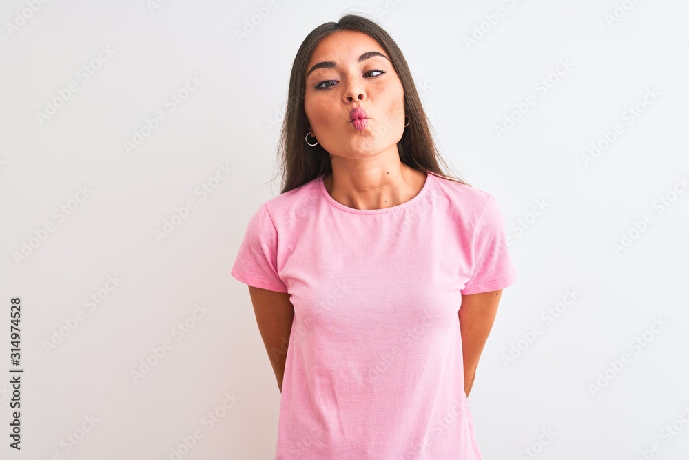 Young beautiful woman wearing pink casual t-shirt standing over isolated white background making fish face with lips, crazy and comical gesture. Funny expression. Young beautiful woman wearing pink casual t-shirt standing over isolated white background making fish face with lips, crazy and comical gesture. Funny expression.