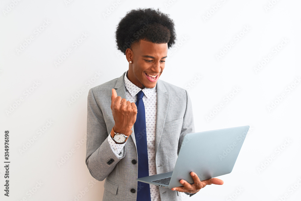 Young african american businessman using laptop standing over isolated white background screaming proud and celebrating victory and success very excited, cheering emotion Young african american businessman using laptop standing over isolated white background screaming proud and celebrating victory and success very excited, cheering emotion