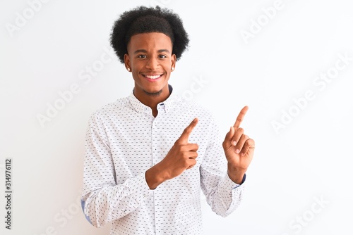 Young african american man wearing elegant shirt standing over isolated white background smiling and looking at the camera pointing with two hands and fingers to the side.