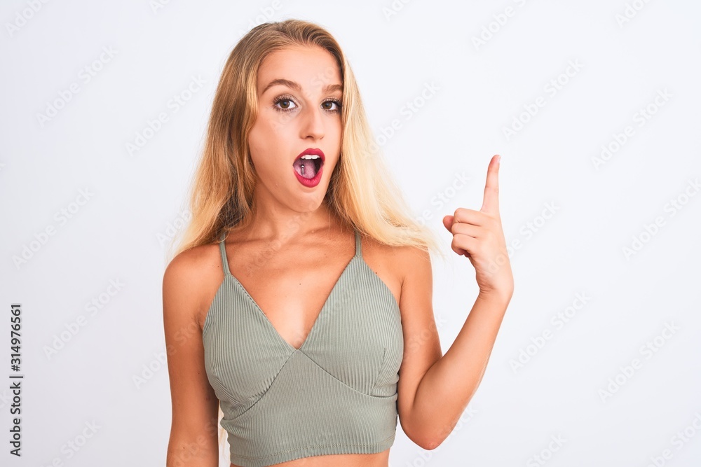 Young beautiful woman wearing casual green t-shirt standing over isolated white background pointing finger up with successful idea. Exited and happy. Number one. Young beautiful woman wearing casual green t-shirt standing over isolated white background pointing finger up with successful idea. Exited and happy. Number one.