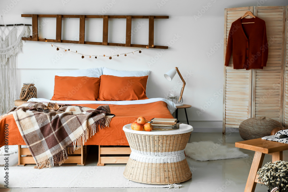 Naklejka Stylish interior of room with big comfortable bed and autumn decor
